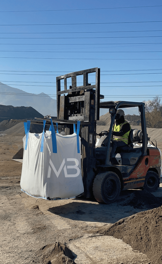 Un montacargas levantando un maxisaco en un entorno industrial.