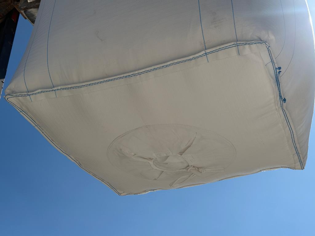 Maxisaco visto desde abajo, mostrando su forma cuadrada y costuras, contra un cielo azul claro.